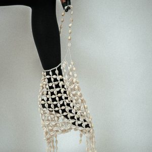 A bag crafted entirely from cowrie shells. Once home to sea creatures, now a sanctuary for your belongings. 180 hours of intricate threading, performance, and craftsmanship.